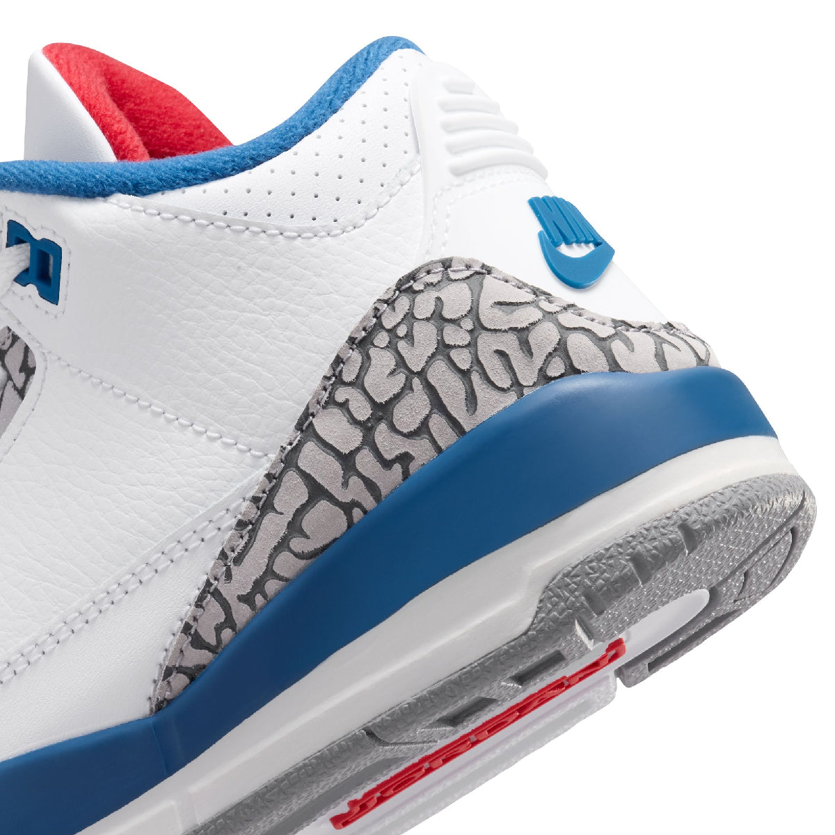 Close-up of a white leather sneaker showing the heel and side panel, with a gray elephant print overlay, blue midsole, red lining, and blue Nike swoosh on a white background.