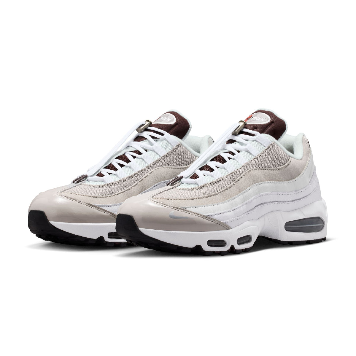 A pair of Nike Air Max 95 sneakers in a light beige and white colorway with dark brown accents on the tongue, heel, and outsole.
