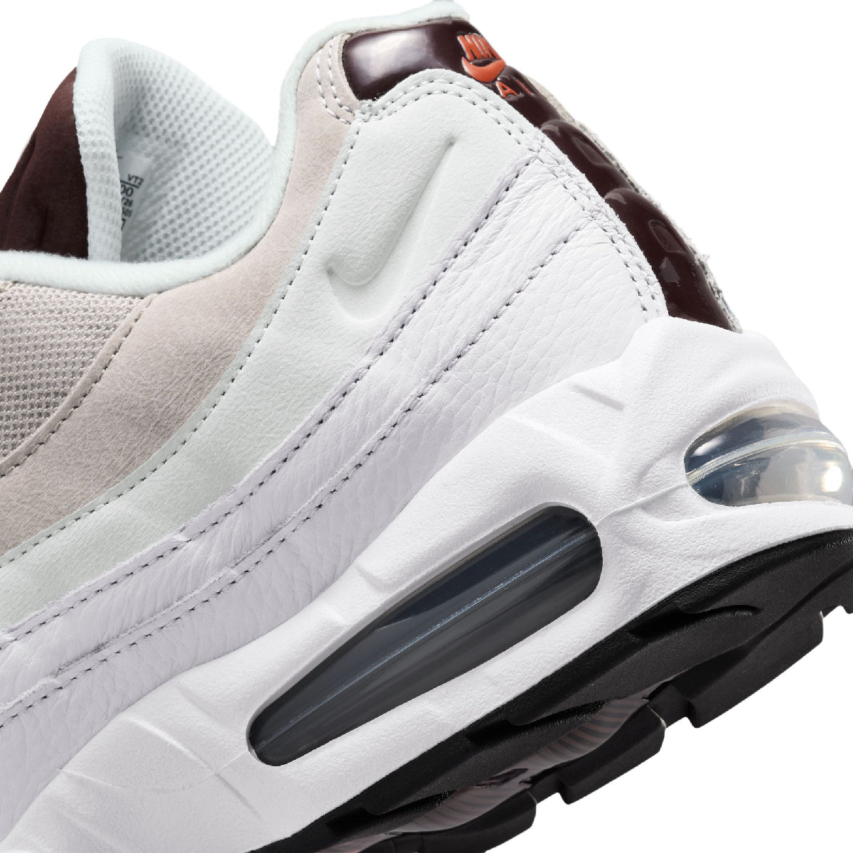 Close-up of a Nike sneaker showing the white leather and mesh upper, dark brown heel tab, and black and translucent air cushioning unit.