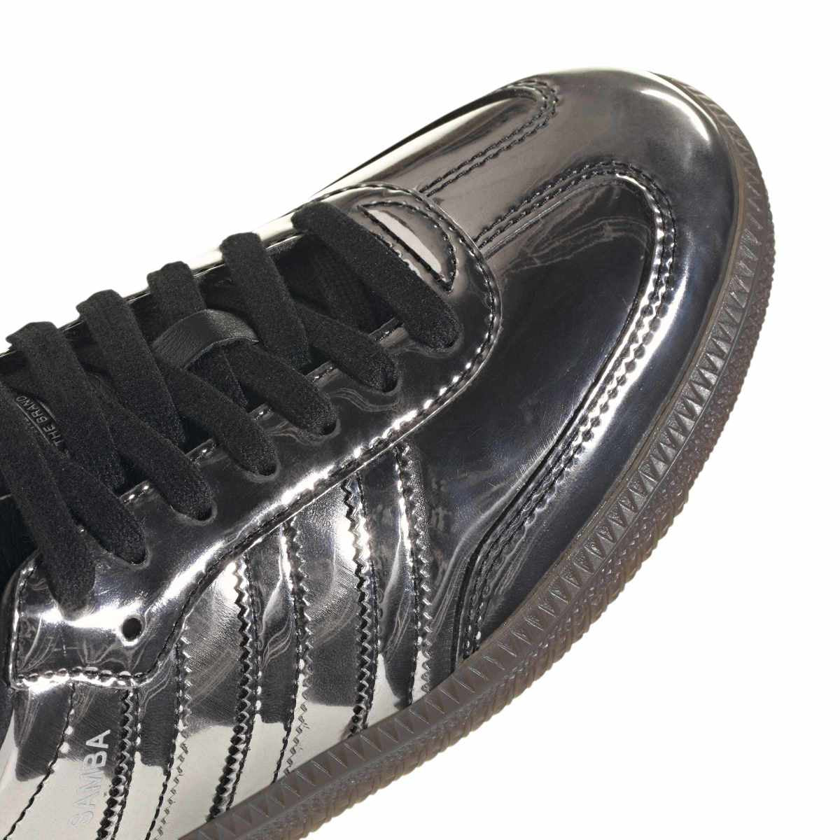 Silver metallic sneaker with black laces on a white background