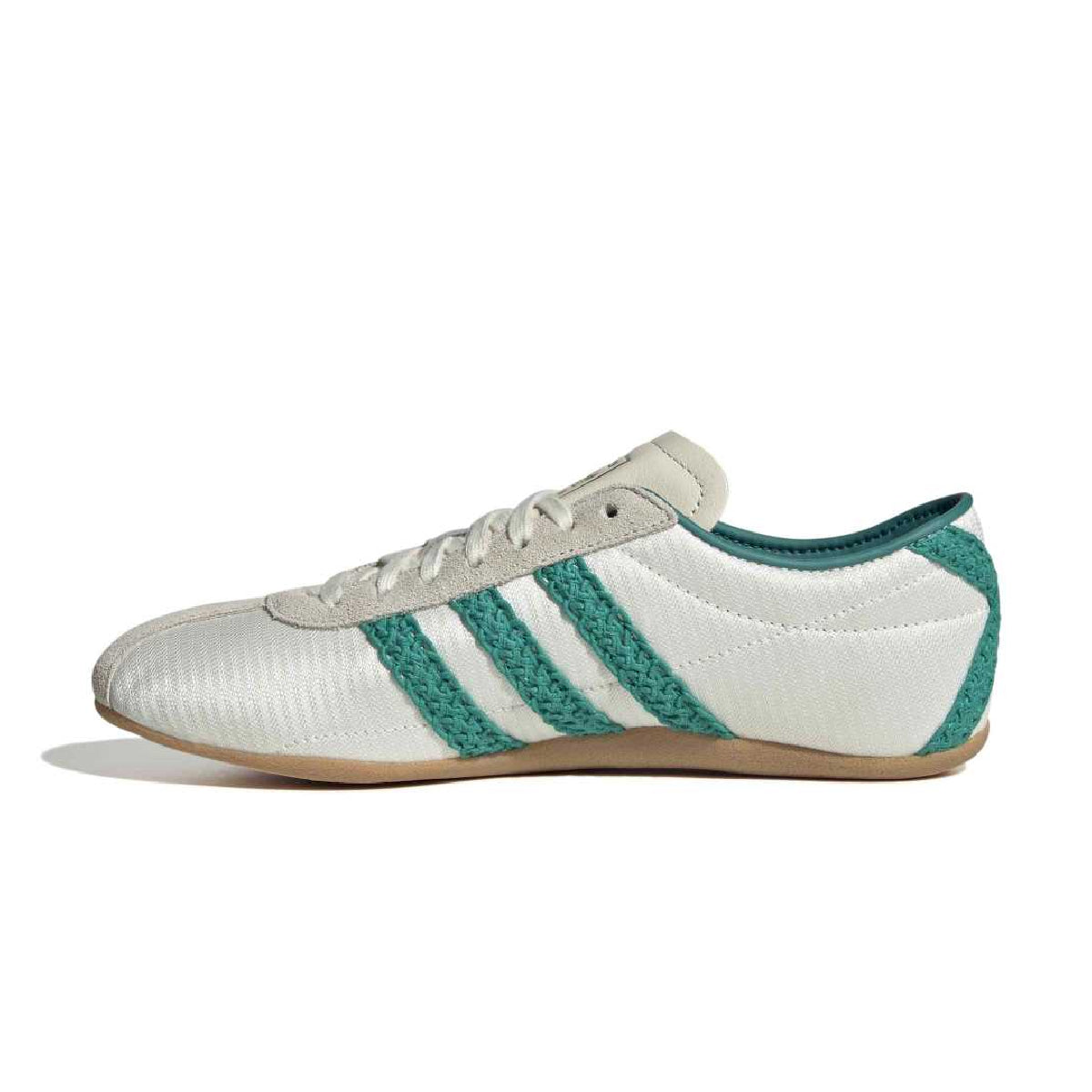 A white low-top sneaker with three dark navy stripes on the side, a beige tongue label, and a gum brown sole, shown in profile against a white background.