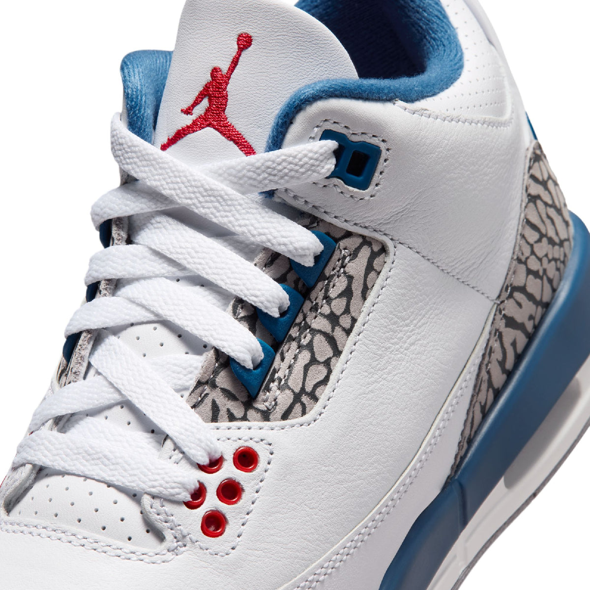 Close-up of a white Air Jordan sneaker with blue accents, red Jumpman logo on the tongue, and gray elephant print overlays.