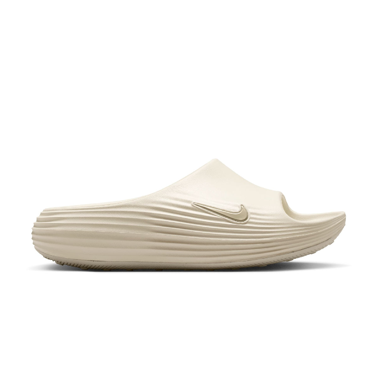 A single Nike slip-on shoe in a light cream or off-white color, featuring a ribbed sole and a tonal Swoosh logo on the side, set against a plain white background.