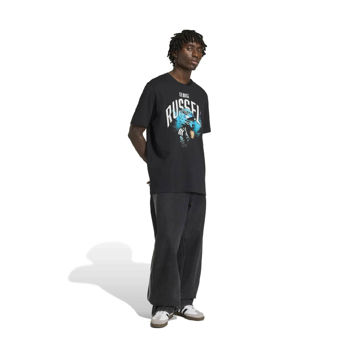 A model stands against a white background wearing a black graphic t-shirt with 'RUSSELL' and a blue player illustration, paired with black sweatpants and white sneakers.