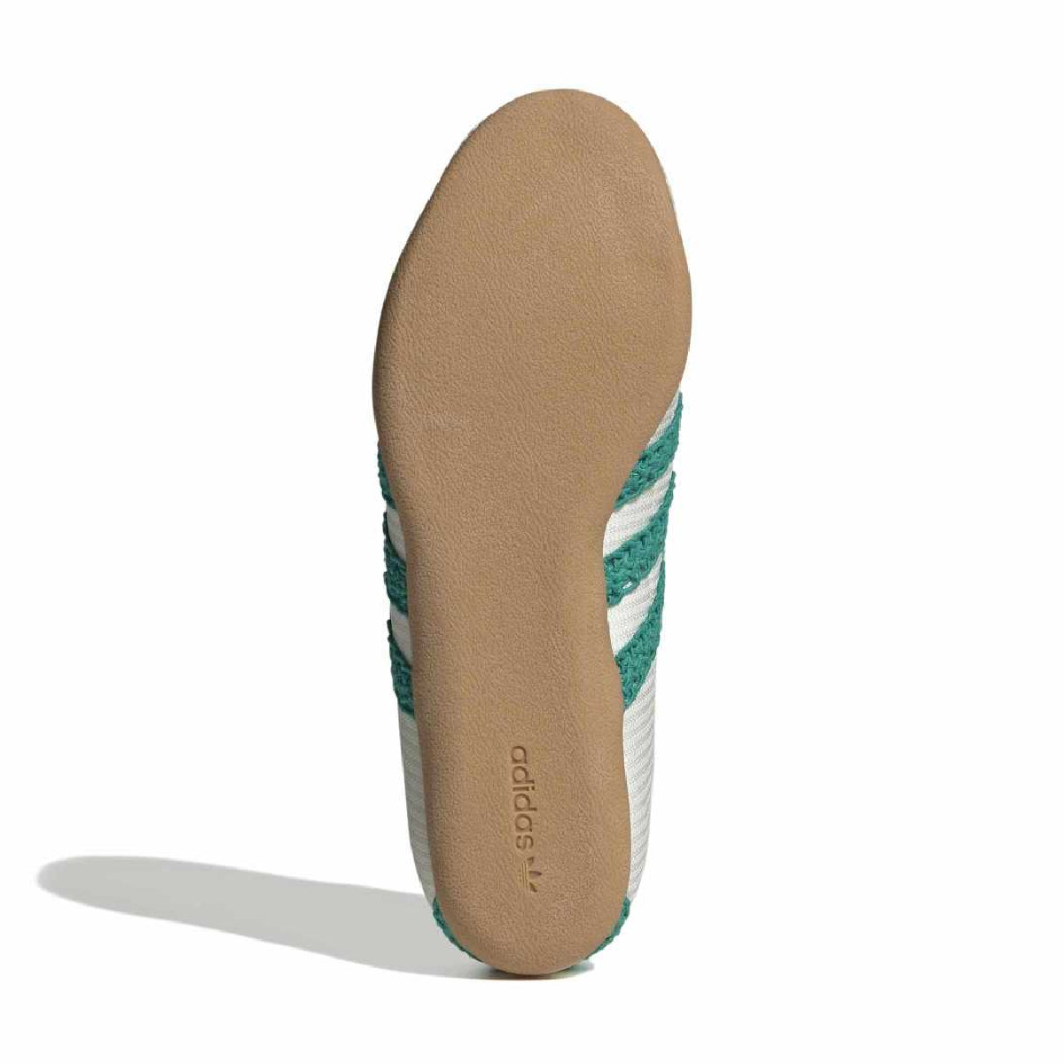 The outsole view of an Adidas sneaker, showing a tan suede midsole with the Adidas logo and green and white knit stripes on the side, set against a plain white background.