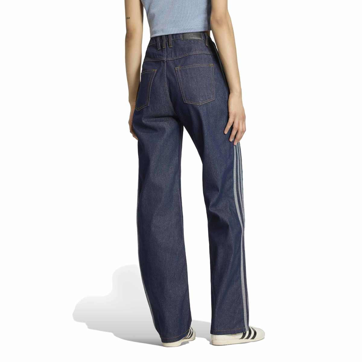 A model shown from the back wearing dark blue wide-leg denim jeans with white side stripes, a light blue top, and white sneakers with black stripes, set against a plain white background.