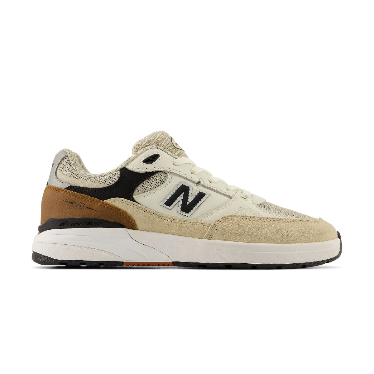 A New Balance sneaker in beige suede and mesh with black accents, a brown heel tab, and a white midsole, shown in a side profile on a white background.